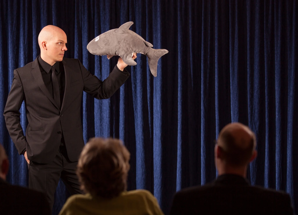 Florian Severin holds a plush shark aloft on stage
